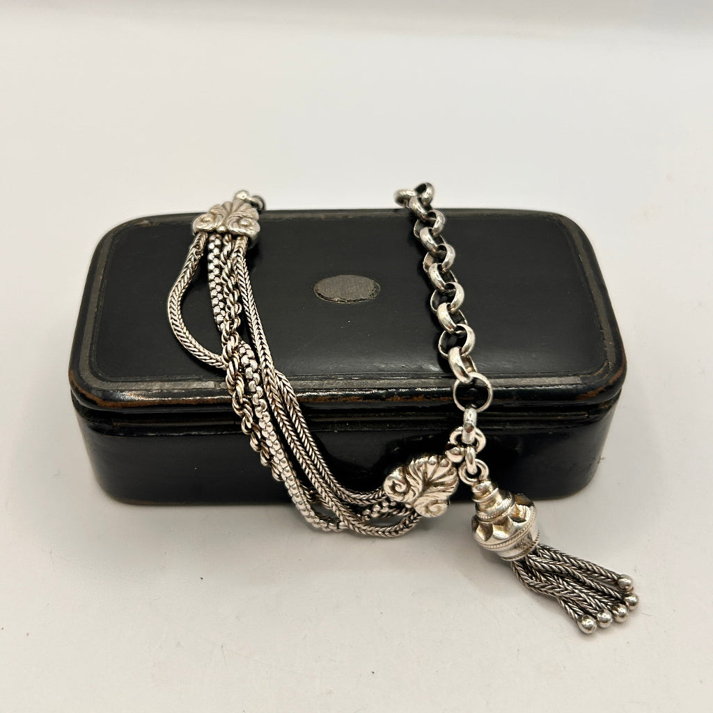 Silver necklace with tassel on a black jewelry box