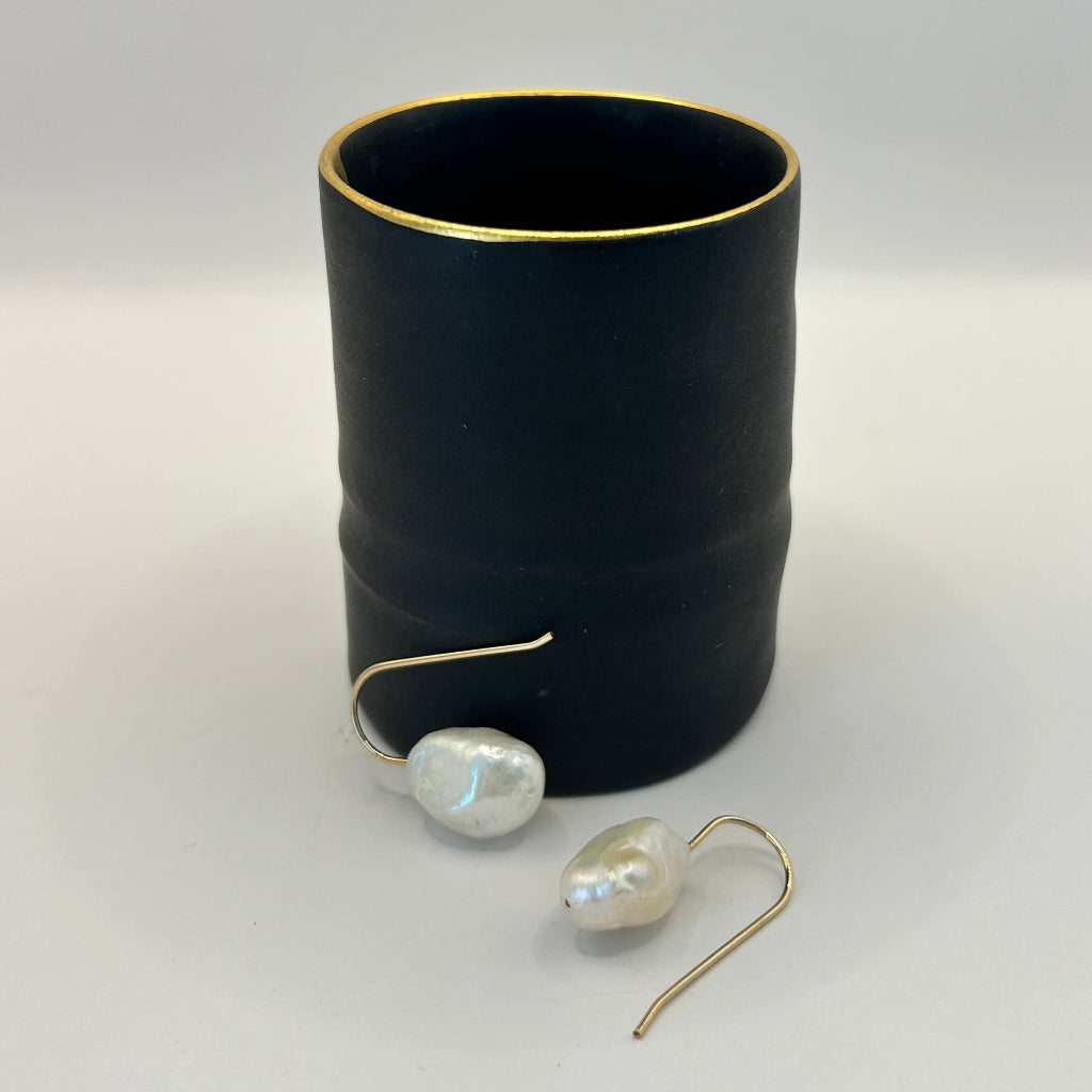 Baroque pearl hook earrings against a pot by ceramicist Fliff Carr