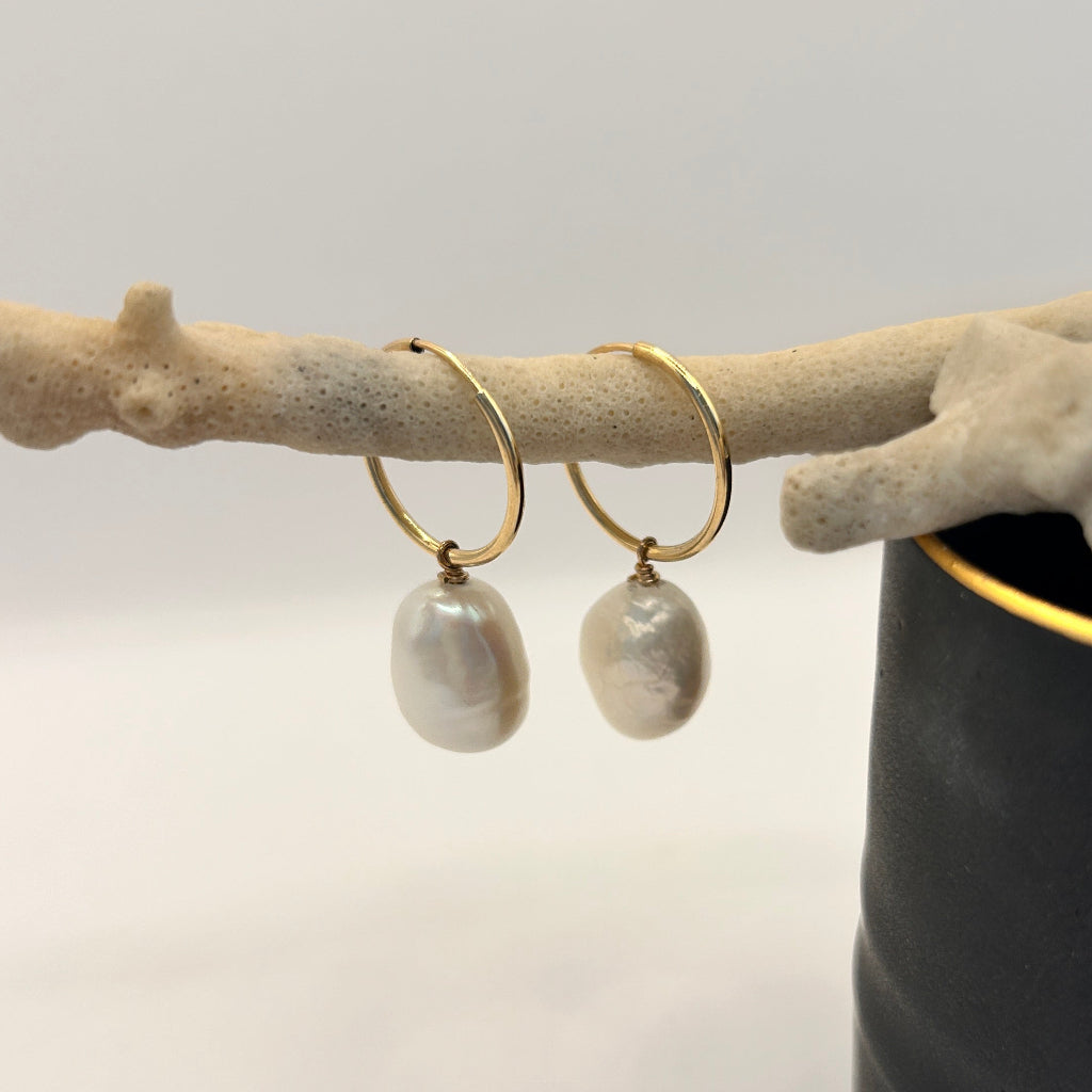 Baroque pearl hoops against a Fliff Carr ceramic pot