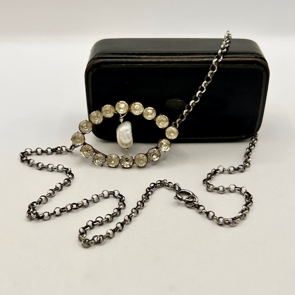 Black rectangular box  with a chain necklace  featuring gemstones and a pearl wrapped around it by Badgers Velvet 