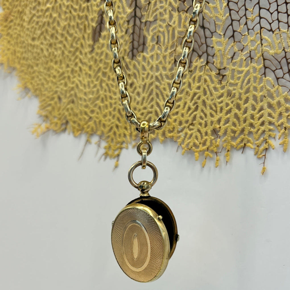 Gold Victorian chain necklace and locket  with a clasp on a textured sea coral background