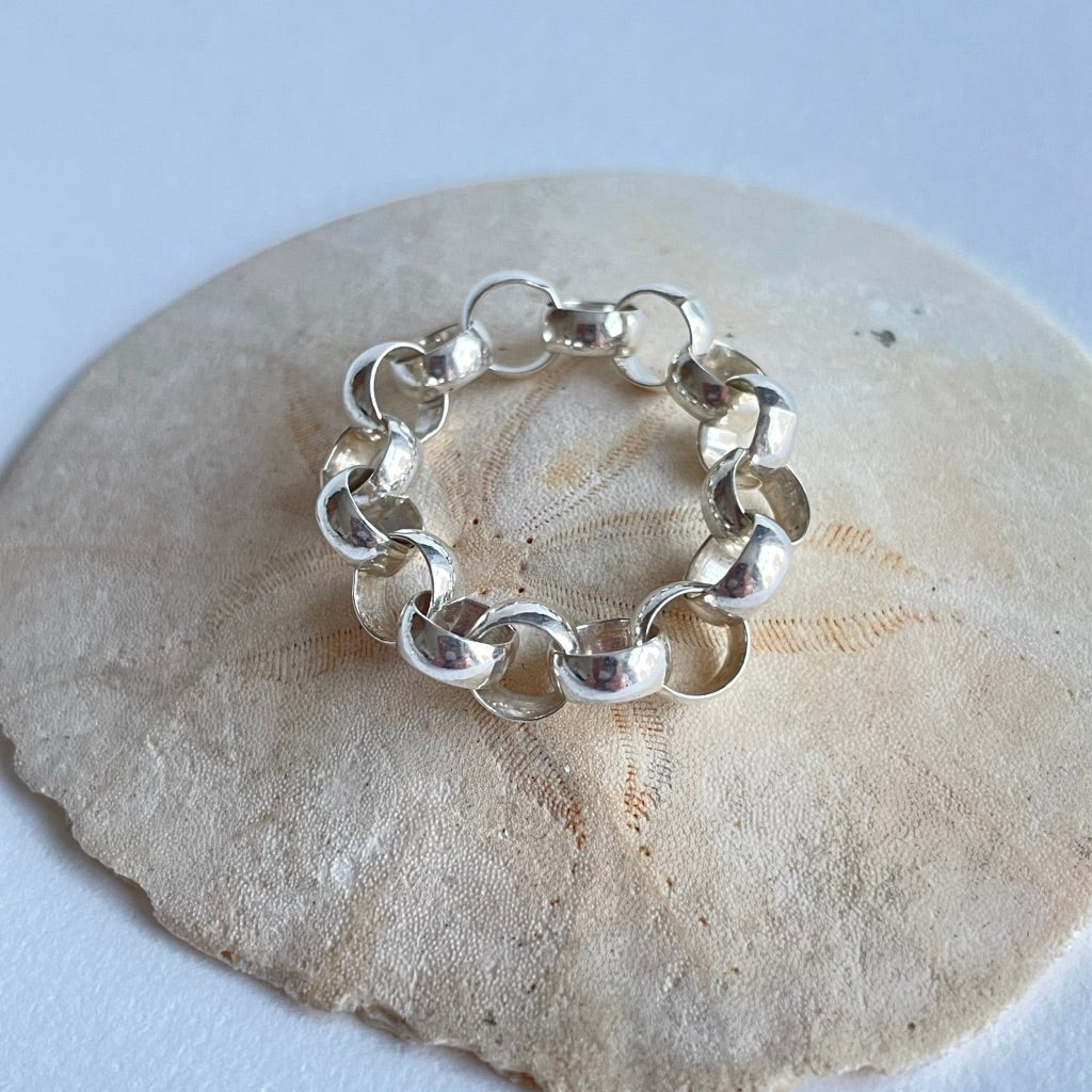 A silver chunky belcher chain ring photographed on a shell background.